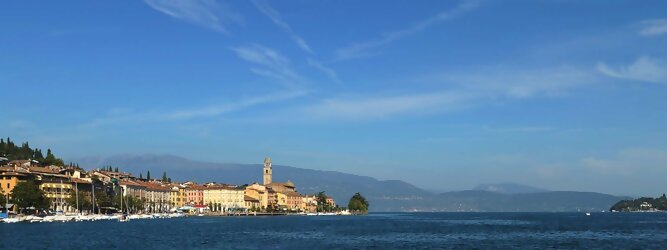 Trip Ungarn beliebte Urlaubsziele am Gardasee -  Mit einer Fläche von 370 km² ist der Gardasee der größte See Italiens. Es liegt am Fuße der Alpen und erstreckt sich über drei Staaten: Lombardei, Venetien und Trentino. Die maximale Tiefe des Sees beträgt 346 m, er hat eine längliche Form und sein nördliches Ende ist sehr schmal. Dort ist der See von den Bergen der Gruppo di Baldo umgeben. Du trittst aus deinem gemütlichen Hotelzimmer und es begrüßt dich die warme italienische Sonne. Du blickst auf den atemberaubenden Gardasee, der in zahlreichen Blautönen schimmert - von tiefem Dunkelblau bis zu funkelndem Türkis. Majestätische Berge umgeben dich, während die Brise sanft deine Haut streichelt und der Duft von blühenden Zitronenbäumen deine Nase kitzelt. Du schlenderst die malerischen, engen Gassen entlang, vorbei an farbenfrohen, blumengeschmückten Häusern. Vereinzelt unterbricht das fröhliche Lachen der Einheimischen die friedvolle Stille. Du fühlst dich wie in einem Traum, der nicht enden will. Jeder Schritt führt dich zu neuen Entdeckungen und Abenteuern. Du probierst die köstliche italienische Küche mit ihren frischen Zutaten und verführerischen Aromen. Die Sonne geht langsam unter und taucht den Himmel in ein leuchtendes Orange-rot - ein spektakulärer Anblick.